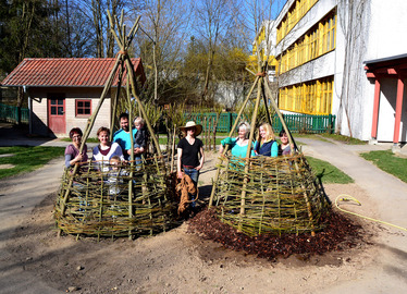  - Erzieherinnen und Erzieher  aus verschiedenen KiTa’s im Landkreis Regen bei ihrem Garten-Projekt in Teisnach mit Sozialpädagogin Franziska Regner (re.) und KiTa-Leiterin Anita Aichinger (2.v.li.). Im Laufe des Jahres treiben die eingegrabenen Weidenstangen und -triebe aus und bilden das Dach. Foto: Eder/Landkreis Regen