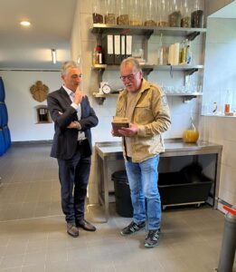 Kammermeier (re.) zeigt Landrat Dr. Raith das alte Buch aus der Schlossbibliothek, in dem sich das Rezept findet, das ihn zum Kartoffelbrand Woidka inspiriert hat. Foto: Iris Gehard / Landratsamt Regen