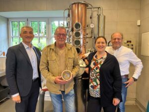 Blick in die Brennerei des Guts Oberfrauenau (v.li.): Landrat Dr. Ronny Raith, Brennmeister und Geehrter Herbert Kammermeier und Inhaberehepaar Alexandra und Benedikt von Poschinger vor der Brennblase, in der schon viel edles Hochprozentiges entstanden ist. Foto: Iris Gehard / Landratsamt Regen