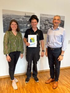 „Heute haben wir einen Glücksbringer im Haus“, so Landrat Dr. Ronny Raith (re.) anlässlich der Übergabe der Klimapakt-Urkunde an Manuel Ertl. Über die erfolgreiche Teilnahme des Kaminkehrermeisters freute sich auch Wirtschaftsreferentin des Landkreises Teresa Sitzberger. Foto: Iris Gehard / Landratsamt Regen
