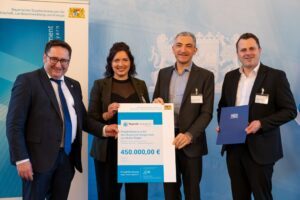 Maria Schneider vom Regionalmanagement des Landkreises, Landrat Dr. Ronny Raith (2.v.re.) und Tobias Wittenzellner, Leiter der Kreisentwicklung nehmen 450000 Euro entgegen, überreicht von Bayerns Wirtschaftsstaatssekretär Tobias Gotthardt (li.). Foto: StMWi/E. Neureuther