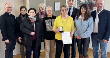 Alle freuen sich mit Sieglinde Gens (6.v.li. im gelben Pulli), v.li.: Pfarrer Tobias Magerl, Maria Hanninger, Jutta Müller-Dietz, Waltraud Weindl, Martha Heimerl, Landrat Dr. Ronny Raith, Claudia Stiglbauer und Bürgermeister Richard Gruber. Foto: Heiko Langer / Landratsamt Regen