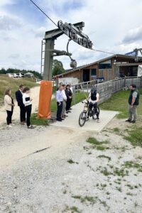 Thomas Eckl (re.), der Leiter der Arberbergbahnen, führte die Besucher durch den neugeschaffenen Bikepark. Am Lift konnten die Gäste erleben, wie einfach die Fahrräder eingehängt werden können. Foto: Heiko Langer / Landkreis Regen
