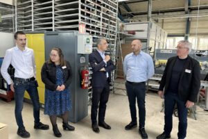 Eric Neveling (re.) erklärte, die Heizbänder hergestellt werden. Elisabeth Unnasch (li.), Bürgermeister Georg Fleischmann (2.v.li.) und Landrat Dr. Ronny Raith (4.v.li.) hörten aufmerksam zu. Sein Kollege Markus Bielmeier führte zuvor durch den Produktionsräume, in denen die Prüfgeräte im Bereich Petrol hergestellt werden. Foto: Heiko Langer / Landratsamt Regen