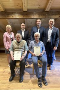 Ein Gruppenbild als Erinnerung: Die Geehrten Konrad Edenhofer (li.) und Herbert Weinberger dürfen Platz nehmen. Es gratulierten, v. li.: Bürgermeisterin Gaby Wittenzellner (Achslach), Vermessungsamtschef Matthias Holstein, Bürgermeister Josef Saller (Gotteszell) und Landrat Dr. Ronny Raith. Foto: Heiko Langer / Landratsamt Regen