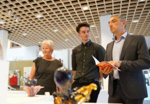 Pletl, Wölfl und Raith (v. li.) betrachten Arbeiten von Lara Lütke aus dem Danner-Schulwettbewerb der Glasfachschule Zwiesel. Foto: Miriam Lange / Landratsamt Regen.