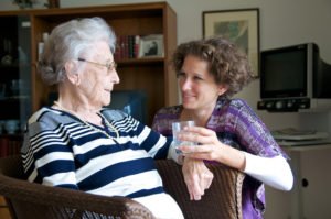 Seniorin wird ein Glas Wasser gereicht