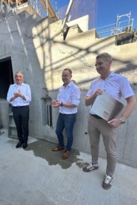 Landrat Dr. Ronny Raith, Schulleiter Andreas Loibl und Architekt Robert Brunner brachten die Zeitkapsel in die Wand ein. Foto: Heiko Langer / Landratsamt Regen