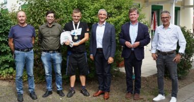 Ein glänzender Empfang: Landrat Dr. Ronny Raith (4. v. li.) und die Regener Werkstätten mit (v. li.) Gruppenleiter Wolfgang Loibl, Werkstattleiter Manuel Troiber, dem Zweiten Vorstandsvorsitzenden Franz Siedersberger und Geschäftsführer Volker Kuppler feierten Goldschwimmer Dorian Burkhardt (3. v. li.). Foto: Miriam Lange / Landkreis Regen