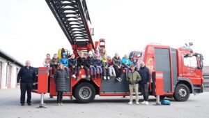 Strahlende Kinder und engagierte Helfende auf und vor dem Einsatzfahrzeug der Stadtfeuerwehr Regen. Reihe unten v. l.: Kreisbrandmeister Atemschutz Hans Richter, Gleichstellungsbeauftragte Sabine Riedl, Kreisjugendamtsmitarbeiter Michael Fenzl und Personalratsvorsitzender Marco Süß.