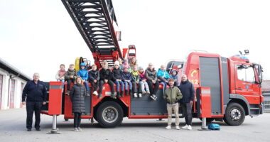 Strahlende Kinder und engagierte Helfende auf und vor dem Einsatzfahrzeug der Stadtfeuerwehr Regen. Reihe unten v. l.: Kreisbrandmeister Atemschutz Hans Richter, Gleichstellungsbeauftragte Sabine Riedl, Kreisjugendamtsmitarbeiter Michael Fenzl und Personalratsvorsitzender Marco Süß.