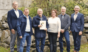 Ehrung nicht am Pfahl, aber vor Naturstein: Landrat Dr. Ronny Raith (rechts) überreichte Matthias Rohrbacher (3. v. li.) im Landratsamt Regen die goldene Dienstzeitenauszeichnung des Bayerischen Naturschutzdienstes. Mit dabei waren (v. li.) Regierungsdirektor Alexander Kraus (Abteilungsleiter Kommunal-, Bau- und Umweltrecht), Hans Günther Knogl (3. Bürgermeister von Grafling) sowie Uwe Behringer und Elisabeth Schröder vom Umweltamt des Landkreises Regen. Foto: Miriam Lange / Landkreis Regen.
