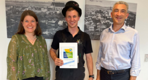 „Heute haben wir einen Glücksbringer im Haus“, so Landrat Dr. Ronny Raith (re.) anlässlich der Übergabe der Klimapakt-Urkunde an Manuel Ertl. Über die erfolgreiche Teilnahme des Kaminkehrermeisters freute sich auch Wirtschaftsreferentin des Landkreises Teresa Sitzberger. Foto: Iris Gehard / Landratsamt Regen