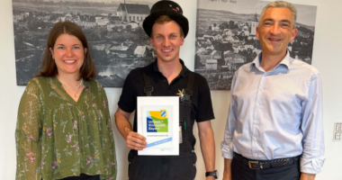 „Heute haben wir einen Glücksbringer im Haus“, so Landrat Dr. Ronny Raith (re.) anlässlich der Übergabe der Klimapakt-Urkunde an Manuel Ertl. Über die erfolgreiche Teilnahme des Kaminkehrermeisters freute sich auch Wirtschaftsreferentin des Landkreises Teresa Sitzberger. Foto: Iris Gehard / Landratsamt Regen