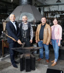 Foto: Schmiedekunst v.li.: Landrat Dr. Ronny Raith, Tobias Haselmayr, Ruhmannsfeldens Bürgermeister Werner Troiber und Wirtschaftsförderin Teresa Sitzberger hätten sich am liebsten gleich im Rahmen eines Schmiedekurses zusammen an die Esse gestellt.