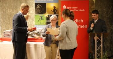 Kreissportbeauftragter Harald Haase und Rita Röhrl überreichen Marion Neubert ihre Auszeichnung, anmoderiert durch Patrick Zens. Foto: Kreisentwicklung Landkreis Regen