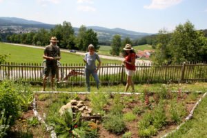 Viola Fuchs (rechts) zeigt Rosemarie Wagenstaller und Klaus Eder ihr neu mit Stauden und Kräutern bepflanztes Beet. Foto: Langer/Landkreis Regen