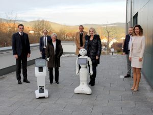 Freyung-Grafenaus Landrat Sebastian Gruber (v.li.), Christian Schmitz (Vorstand der Arberlandkliniken), Regens Landrätin Rita Röhrl, Marcus Plaschke (Geschäftsführer der Kliniken am Goldenen Steig), Professor Dr. Diane Ahrens und Professor Dr. Florian Wahl sowie Lisa-Marie-Hanninger (operative Projektleiterin) vom Technologiecampus Grafenau mit den Robotern Temi (li.) und Pepper. Foto: Langer/Landkreis Regen