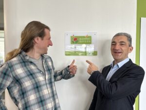 Landrat Dr. Ronny Raith (re.)und Kreisfachberater Martin Straub freuen sich über die Auszeichnung. Das Schild ist bereits in der Eingangshalle angebracht. Foto: Heiko Langer / Landratsamt Regen